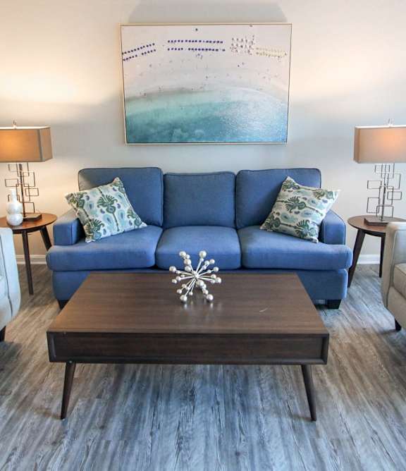 A living room with a blue couch and two white chairs.