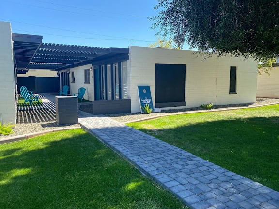 A modern house with a white exterior and a grey walkway leading to the front door.