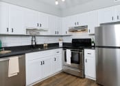 Thumbnail 3 of 23 - Kitchen in Mandarin bay studio apartment in Jacksonville with white cabinets, stainless steel appliances, and modern kitchen light.