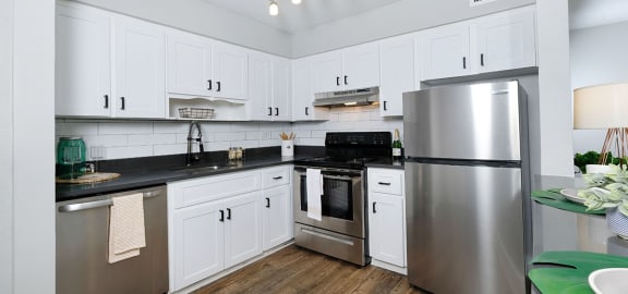Kitchen in Mandarin bay studio apartment in Jacksonville with white cabinets, stainless steel appliances, and modern kitchen light.