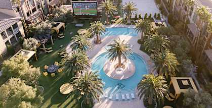 A pool surrounded by palm trees and a building in the background.