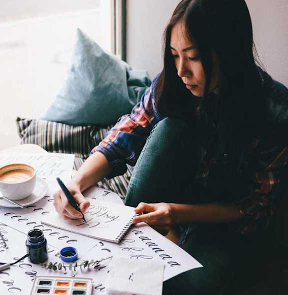 a woman sitting at a table drawing on a piece of paper at Copestone Apartments, Garden City, ID