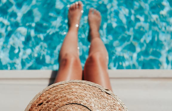 a woman laying on a pool deck with her legs up in the air