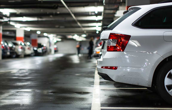 A white car is parked in a dimly lit parking garage.