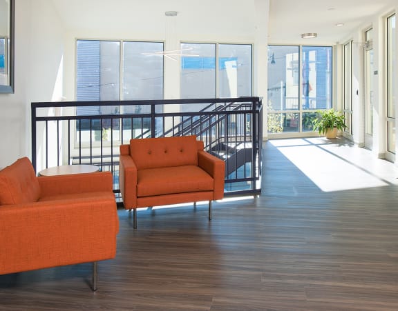 a living room with a couch and a dining table and a refrigerator surrounded by cabinets