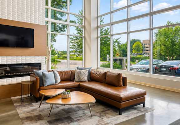 A living room with a brown leather couch and a flat screen TV mounted on the wall.