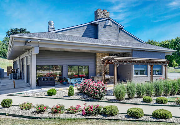 photo of community building with maintained landscaping, a trellis, and well-maintained building