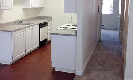an empty kitchen with white cabinets and a wood floor