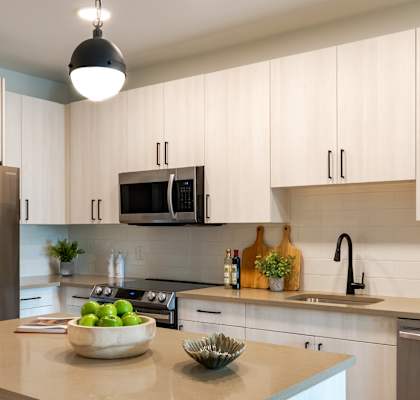 A kitchen with a refrigerator, microwave, and oven.