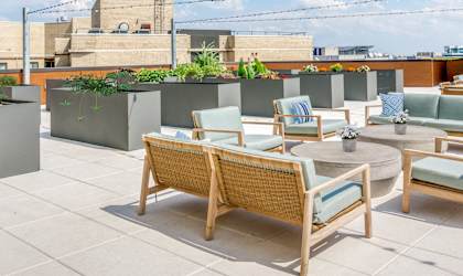 a rooftop terrace with tables and chairs and a building in the background