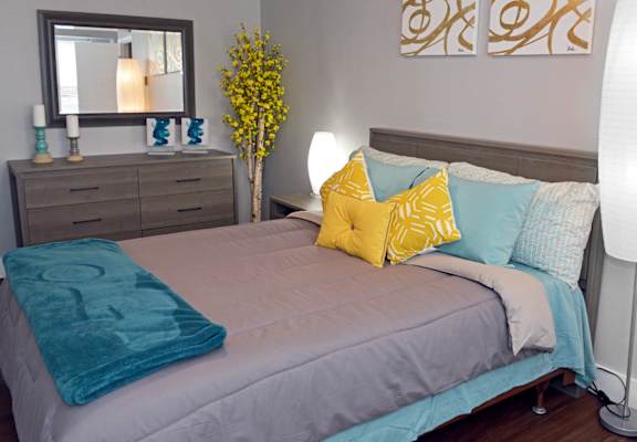 a bedroom with a bed with blue and yellow pillows