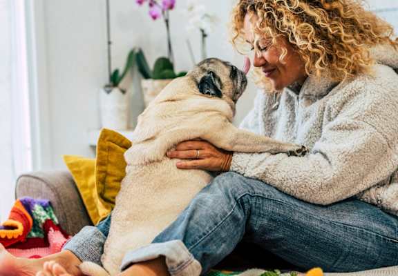 Woman Sitting on Couch Smiling while Holding Pet Dog
