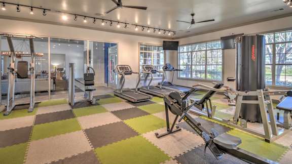 A gym with a variety of equipment including treadmills, elliptical machines, and a rowing machine.