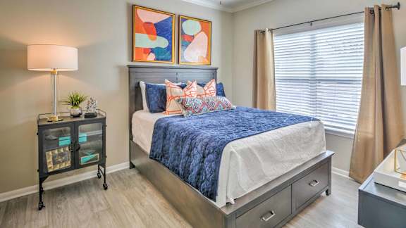 A bedroom with a bed, nightstand, and a lamp.