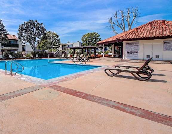 a swimming pool with lounge chairs and a building in the background