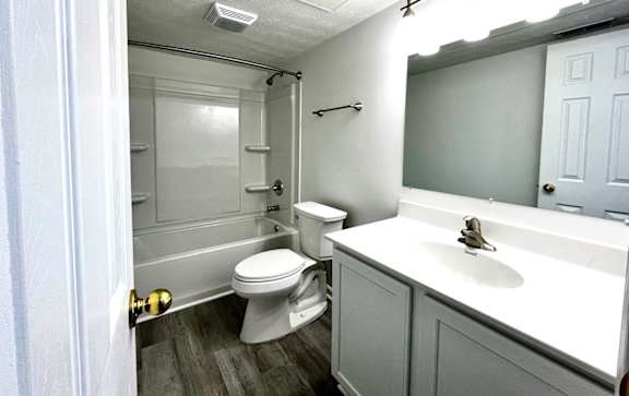 A white toilet is in a small bathroom with a white sink.