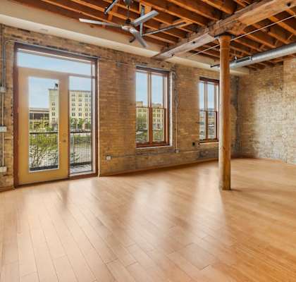 an empty living room with exposed brick walls and wood floors