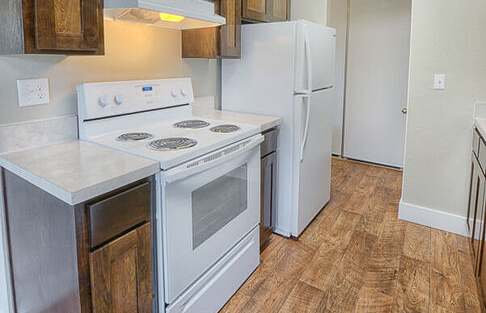 A kitchen with a white stove top oven and white refrigerator.