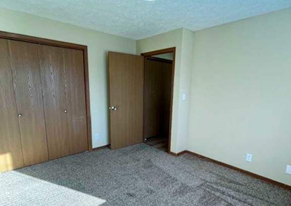 a bedroom with a carpeted floor and two side-by-side closets