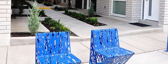 Two blue benches are in front of apartment buildings numbered 6 and 7.