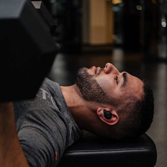 a man laying on a bench in a gym with his head on the bench