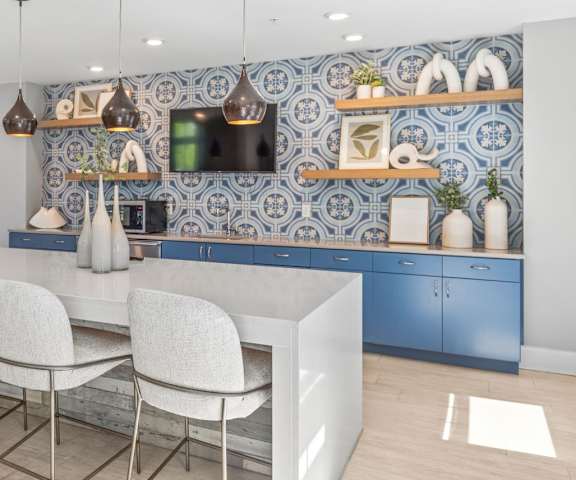 a kitchen with blue cabinets and a white island with chairs at Central Island Square, Daniel Island, SC