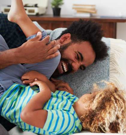 Father Smiling and Playing with Son on Couch