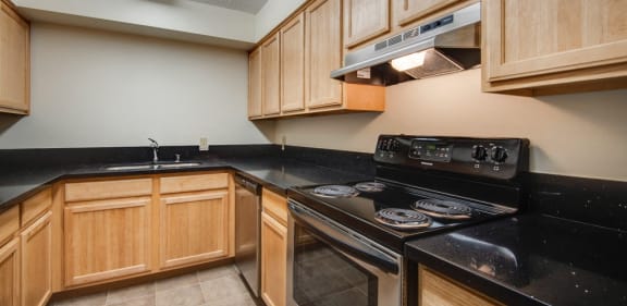 a kitchen with black countertops and wooden cabinets and a stove and oven