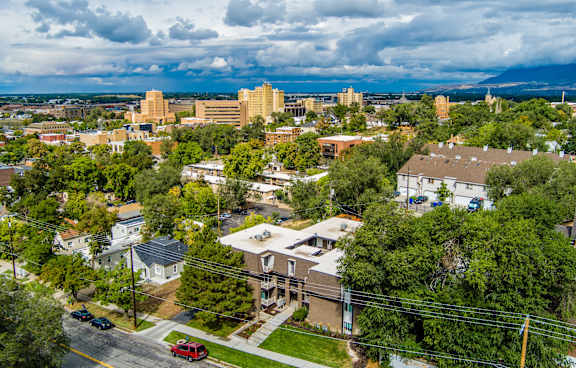 A cityscape with buildings and trees under a cloudy sky.