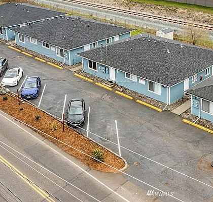 A parking lot with a few cars and a building with a yellow line in front of it.