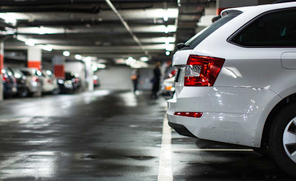 A white car is parked in a dimly lit parking garage at Podium Apartments, Calgary, AB