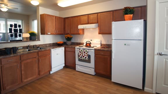 a kitchen with white appliances and wooden cabinets at Arlington Grove apartments & townhomes