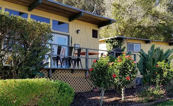A yellow house with a balcony and a garden in front at Salinas Sunset Apartments, Salinas, CA, 93907