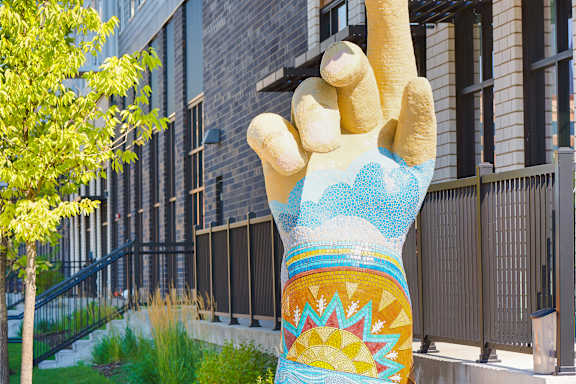 A large hand sculpture is in front of a building at Soul Apartments, St. Paul, MN