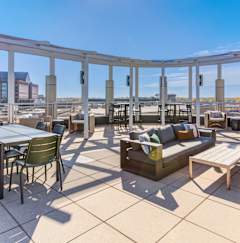 A sunny day on a rooftop patio with tables and chairs.