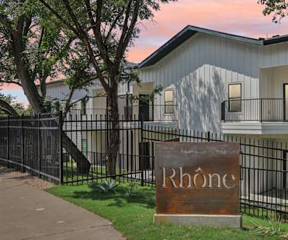 A sign that says Rhone stands in front of a building.