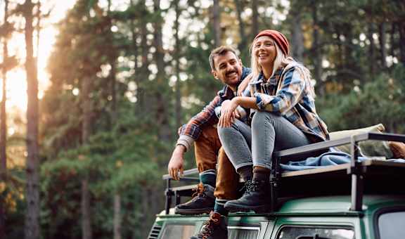 a man and a woman sitting on the roof of a car