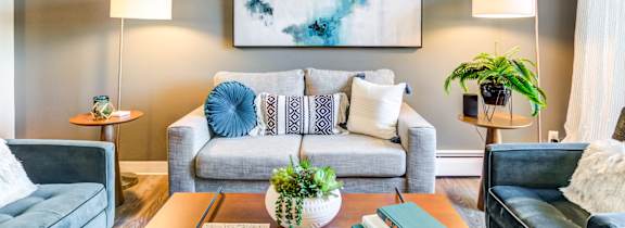 A living room with two couches, a coffee table, and a large painting on the wall.