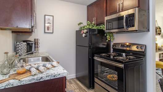 an apartment kitchen with black appliances and granite counter tops and a black stove and refrigerator at Weaver Farm, Florence, 41042