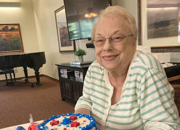 Resident celebrating with patriotic decorated cake at Hilltop Commons Senior Living Apartments, Grass Valley, CA
