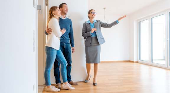 three people standing in an empty room looking at a light fixture