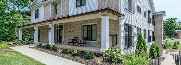 A house with a white and brown exterior and a black railing.