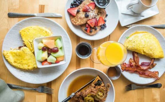 a wooden table topped with plates of breakfast food