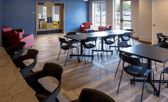 A room with tables and chairs and a ceiling with lights.