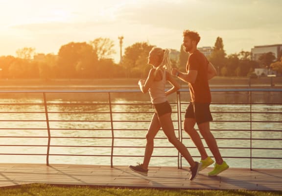 Woman and Man Jogging Near River in Early Morning