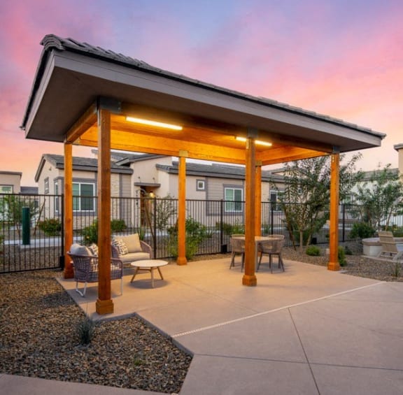 a covered patio with tables and chairs at sunset at Grandstone at Sunrise, Peoria, AZ