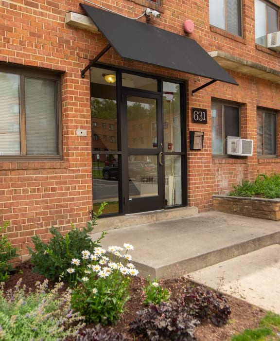 the front door of a brick building with a black awning
