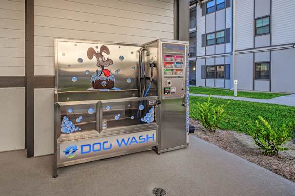 A dog wash machine is outside a building.