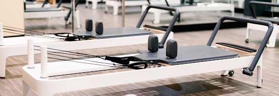 A row of pilates reformers in a gym.