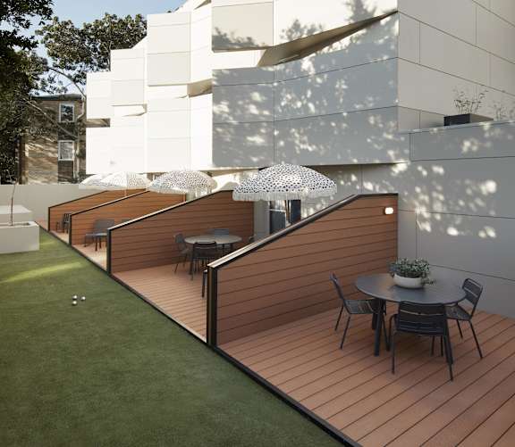 a terrace with a table and chairs in front of a white building